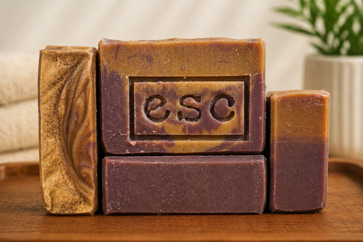 Four bars of soap, orange and purple in color, with 'ESC' branding, the abbreviation of Euphoros Soap Company. A warm spa background.